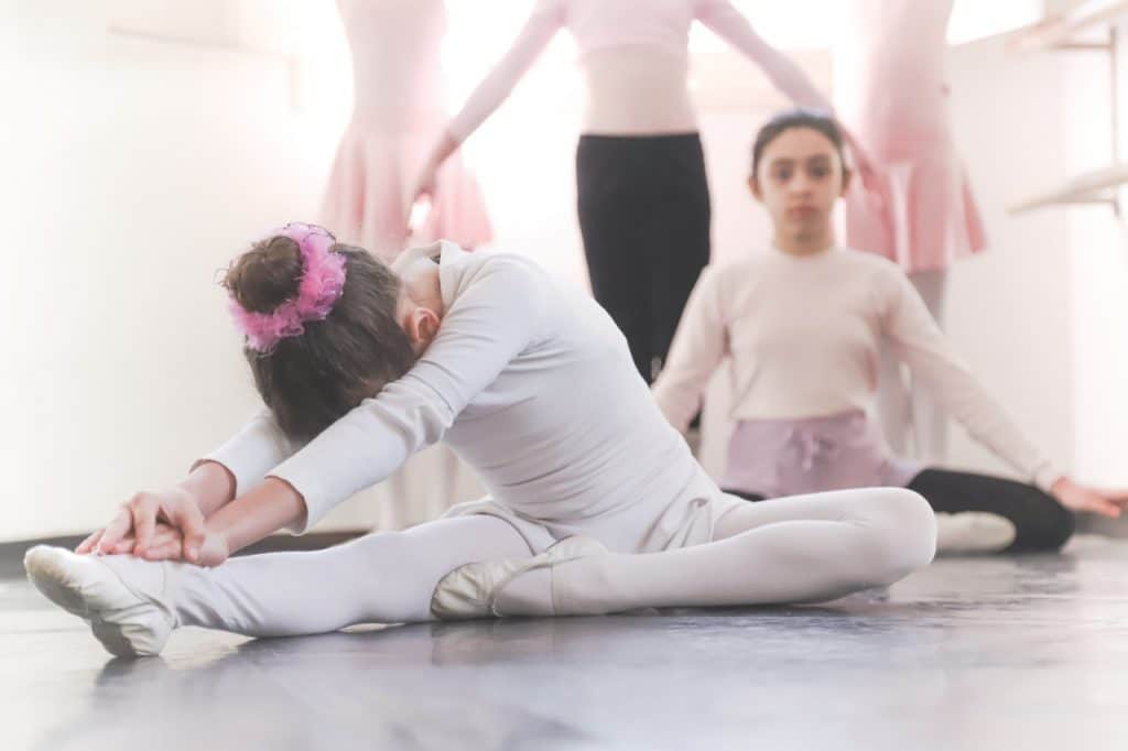 duas bailarinas, iuma delas em alongamento e outra olhando para a foto