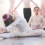 duas bailarinas, iuma delas em alongamento e outra olhando para a foto